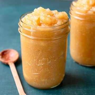 Pint glass jar filled to the top with homemade applesauce.