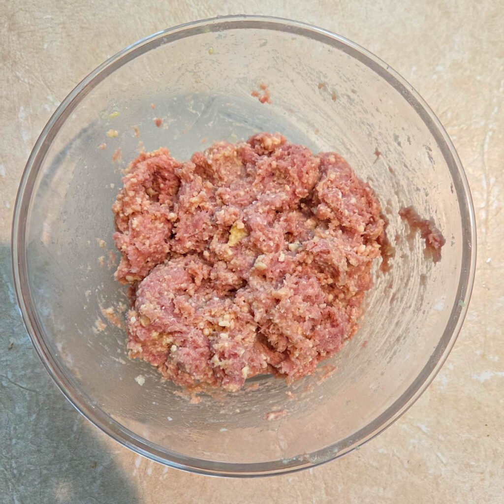 Ground turkey mixed with the panade in a glass bowl.