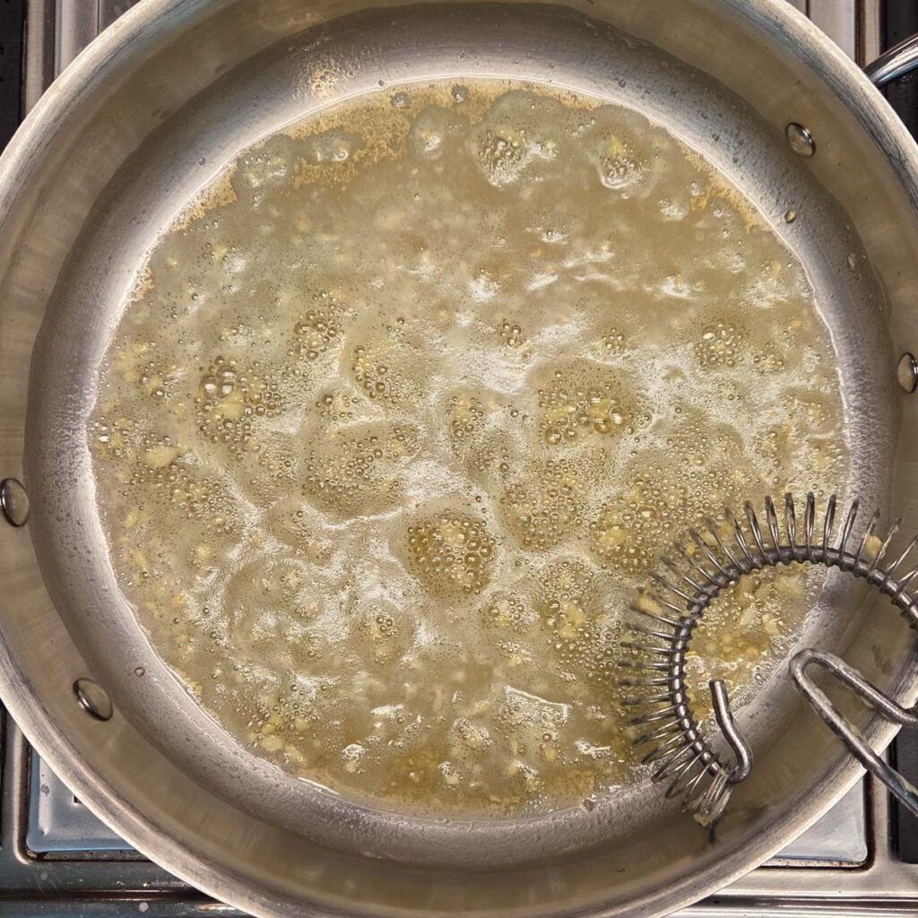 Melted butter and minced garlic sauteeing in a saucepan.