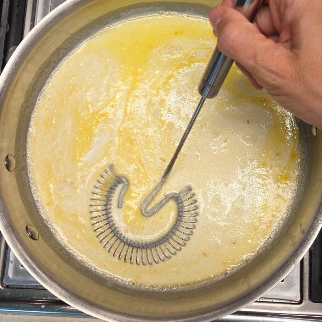 Whisk stirring butter, garlic and heavy cream in a saucepan over heat.