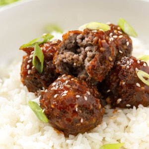 A bite taken out of a sweet and sour meatball to show the tender beef inside.