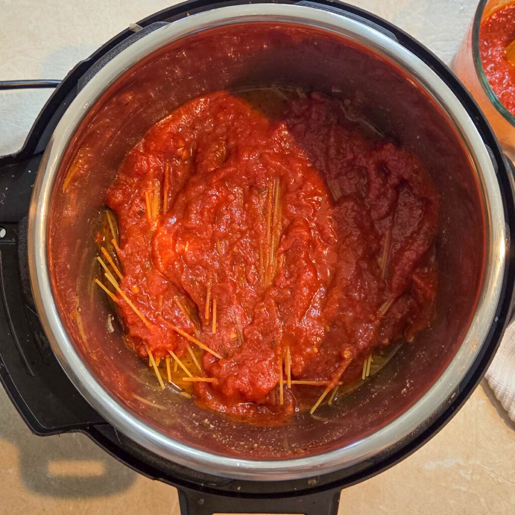 Spaghetti sauce added to the top of the pasta inside the instant pot.