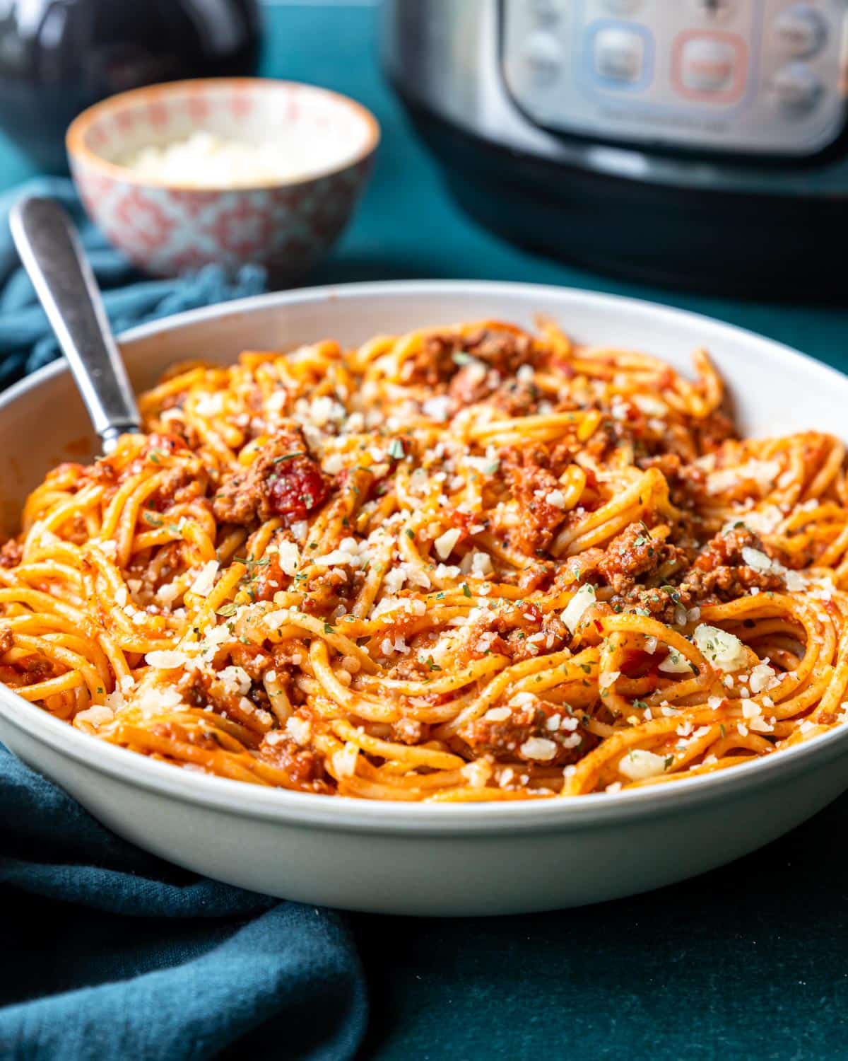Large bowl of spaghetti with meat sauce ready to serve topped with parmesan cheese.