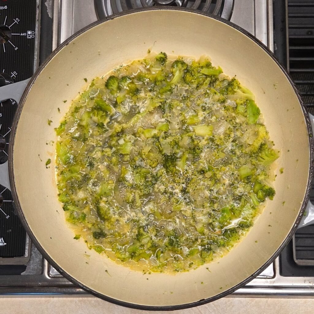 Dutch oven pan with broccoli and onions simmering in chicken broth with chicken base.