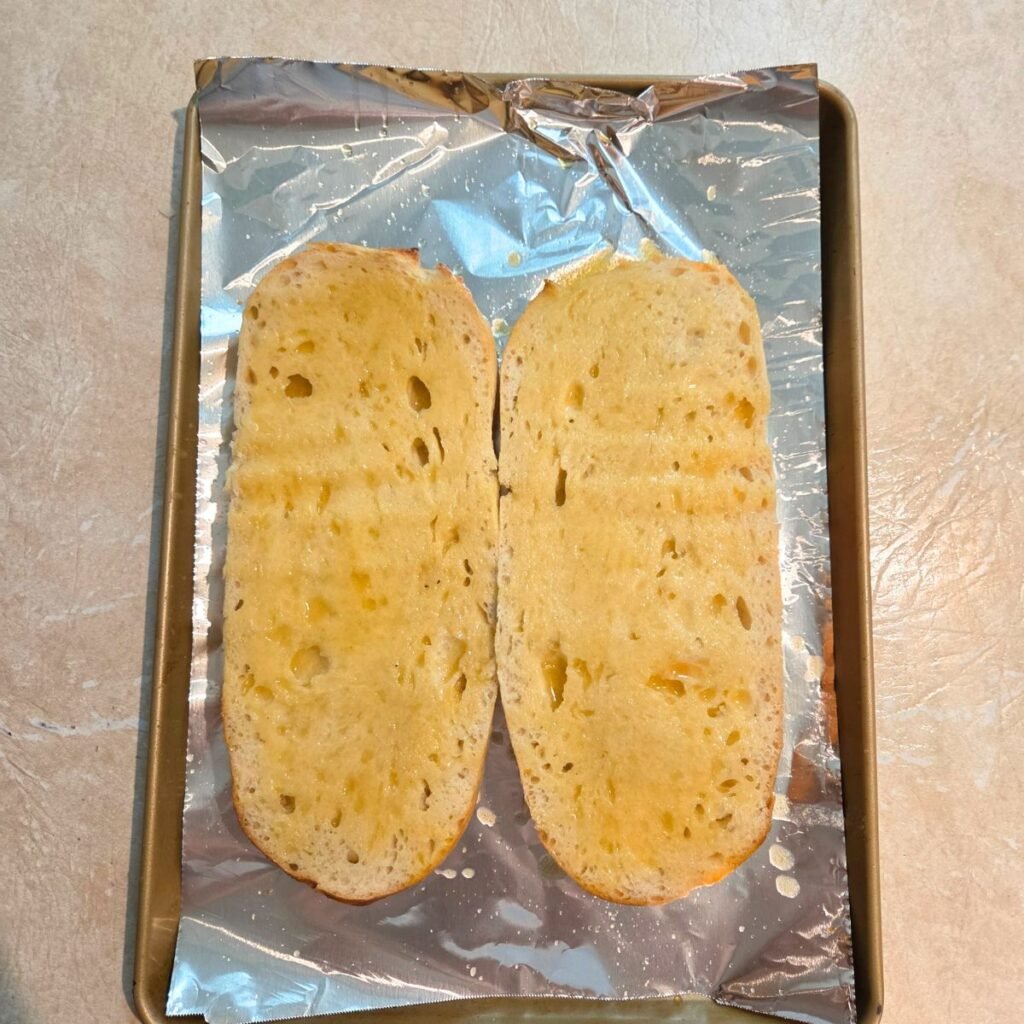 Garlic butter spread over the middle of the halves of an Italian loaf of bread.