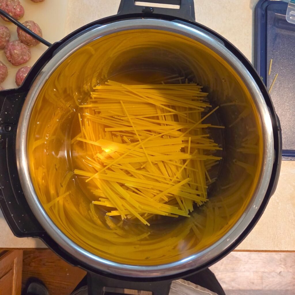 Spaghetti noodles added to the instant pot in a criss cross design.