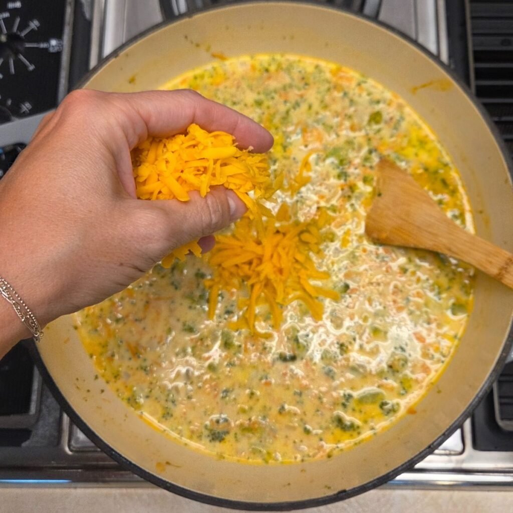 Hand sprinkling in shredded cheddar cheese to the broccoli mixture.