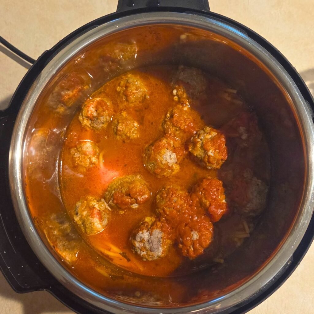 Instant pot filled with cooked spaghetti and meatballs.