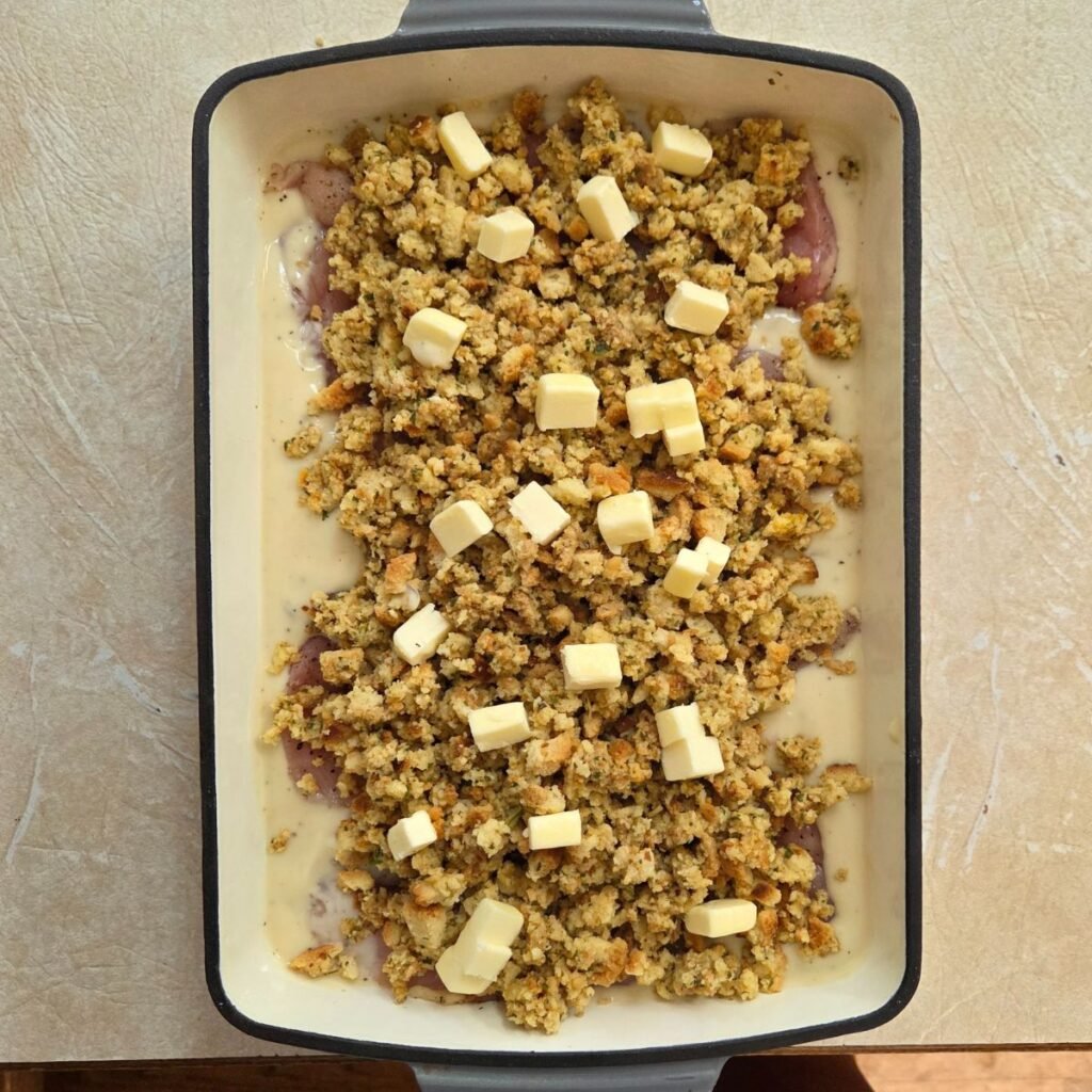 butter cubed on top of stuffing and chicken in a baking dish