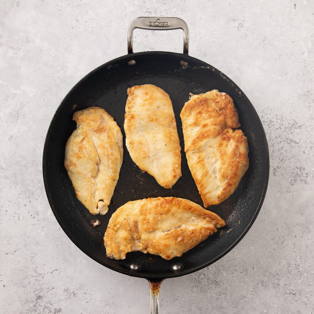 Golden brown cooked chicken breasts in a skillet.