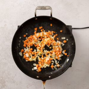 Diced onions and carrots sauteeing in a wok.