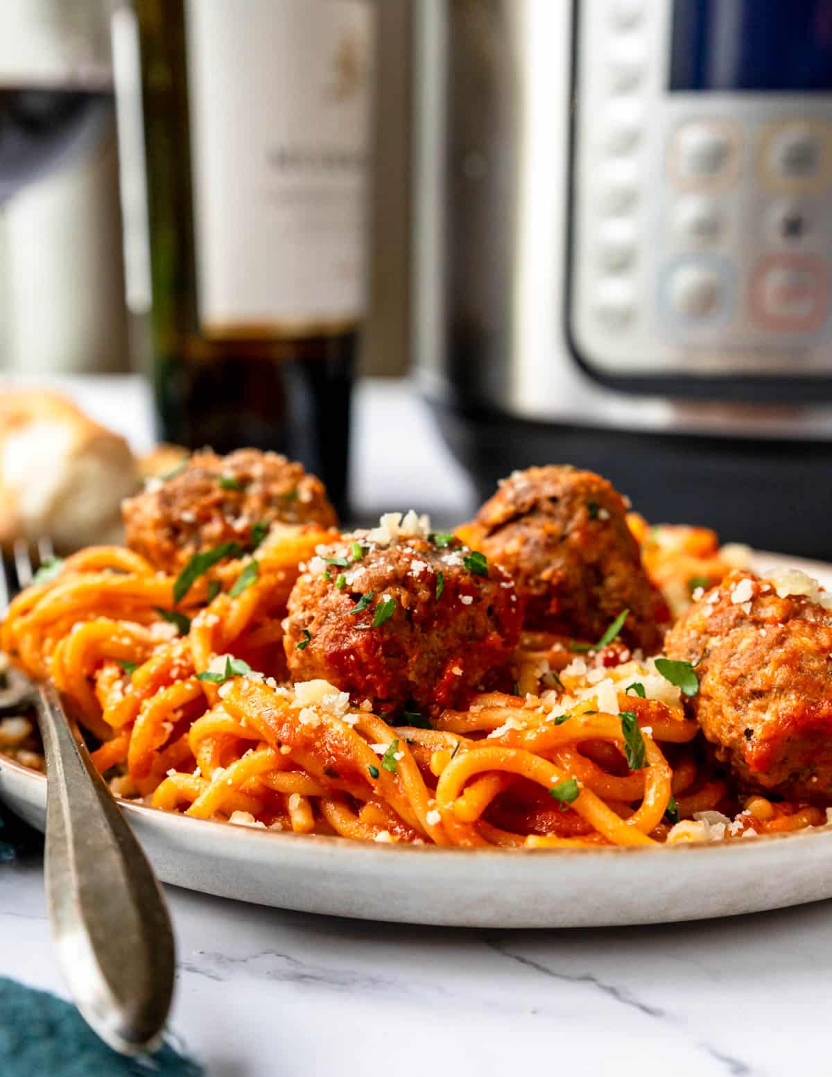 Fork resting on the side of a plate filled with spaghetti and meatballs.