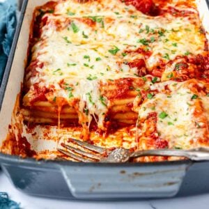 Close up of hot melty cheese over stuffed beef manicotti in a baking dish.