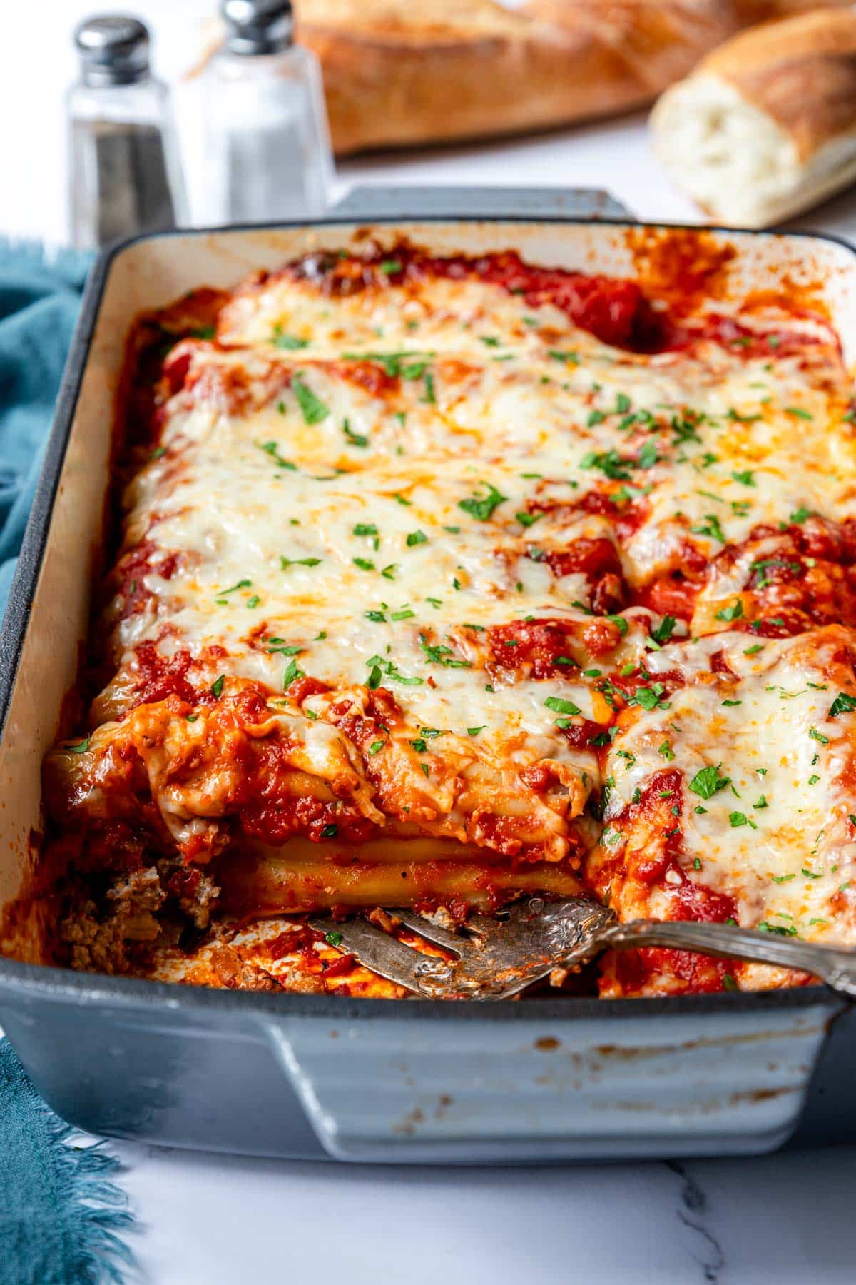 Serving fork resting in a baking dish of hot stuffed beef manicotti dinner.
