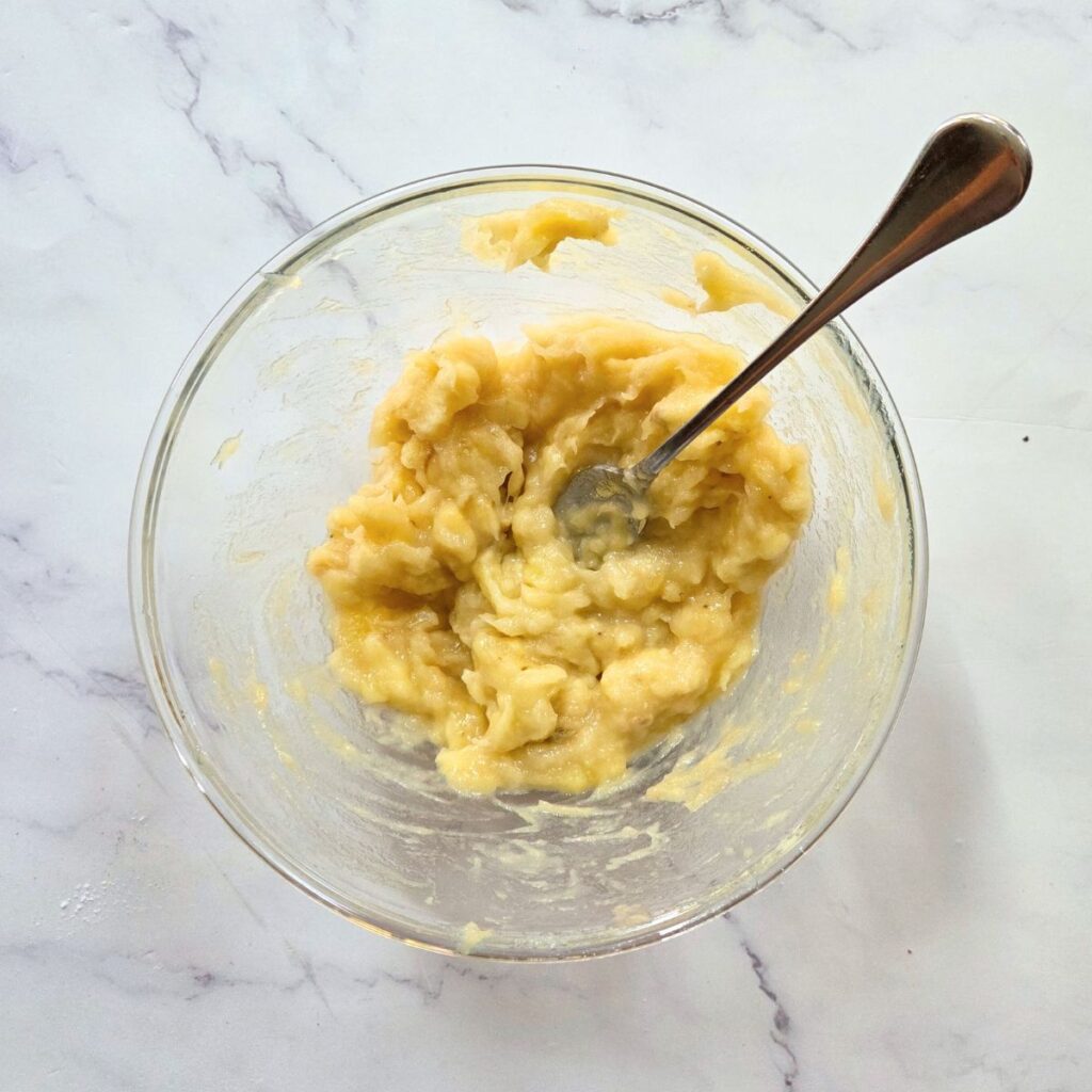 Overripe bananas mashed in a bowl.
