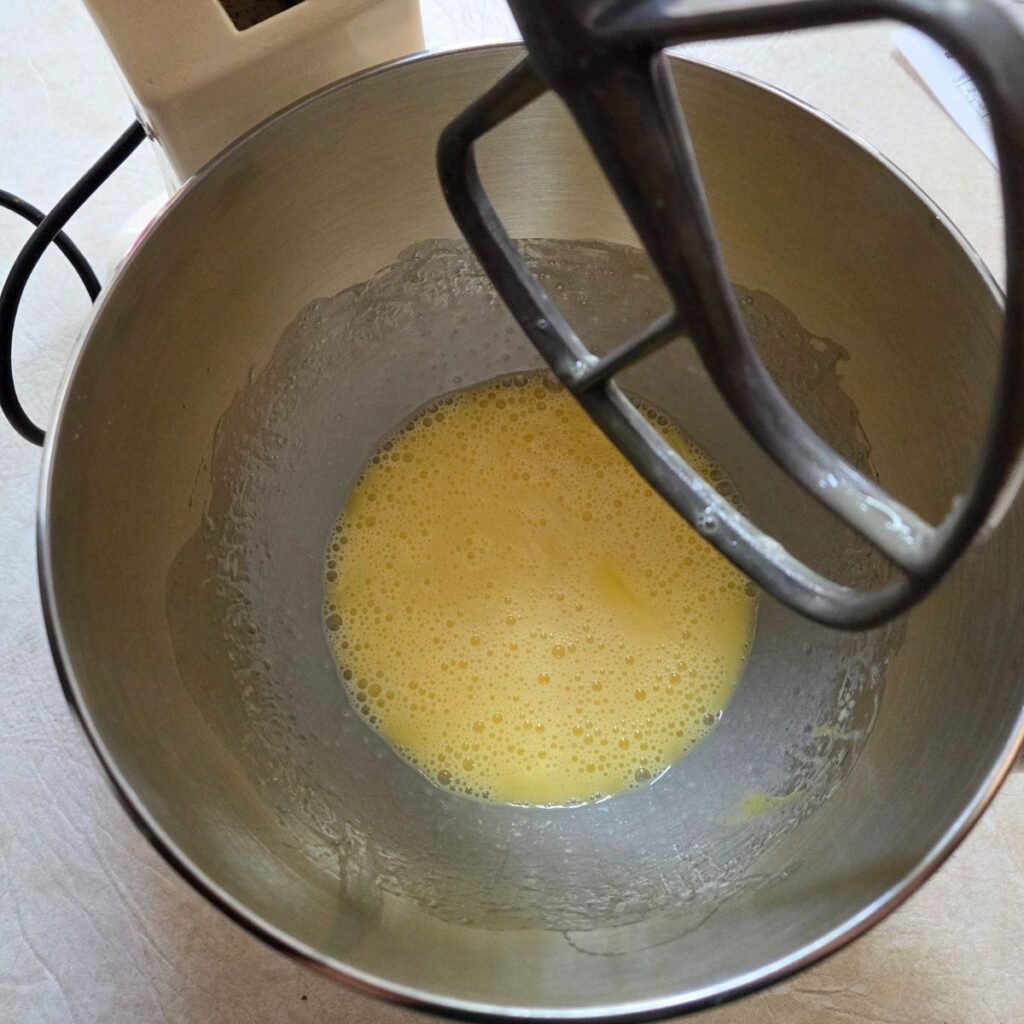 Eggs beat to a light yellow color in a mixing bowl.
