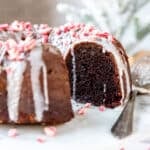 Close up of a chocolate peppermint bundt cake topped with a glaze and chunks of crushed candy cane.