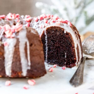 Close up of a chocolate peppermint bundt cake topped with a glaze and chunks of crushed candy cane.