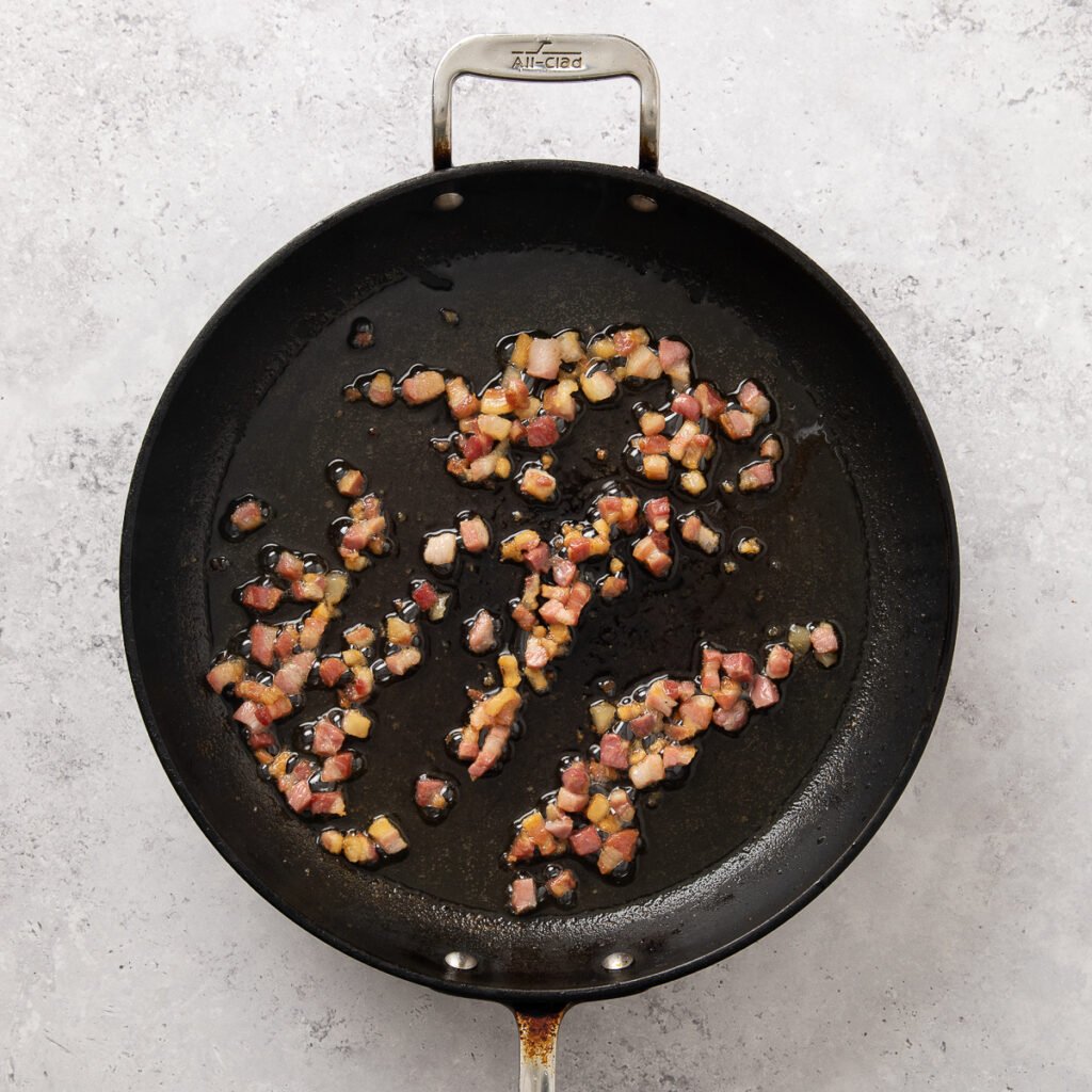 Chopped pancetta sauteeing in skillet.