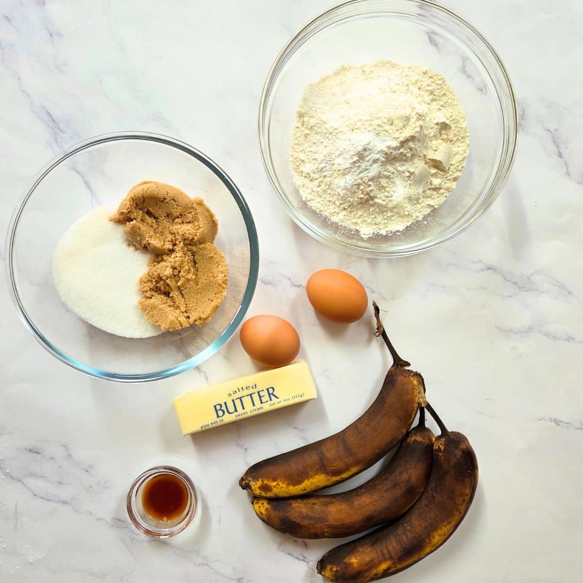 Banana bread ingredients measured into bowls with overripe bananas.