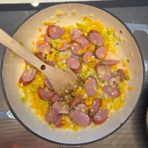 Diced celery, onions and peppers sauteeing in a pan with the andouille sausage.