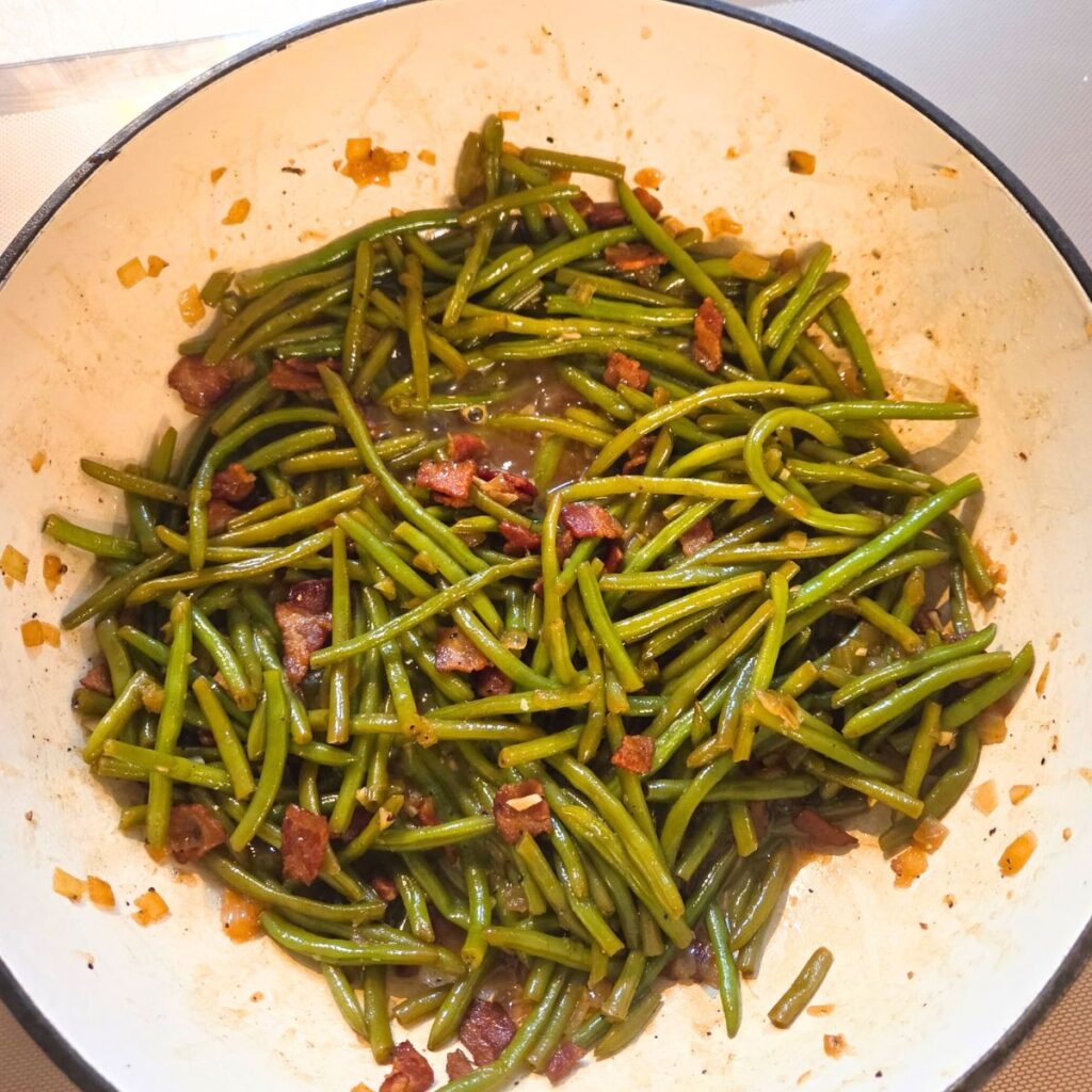 Chopped bacon, onions and green beans added to a Dutch oven.