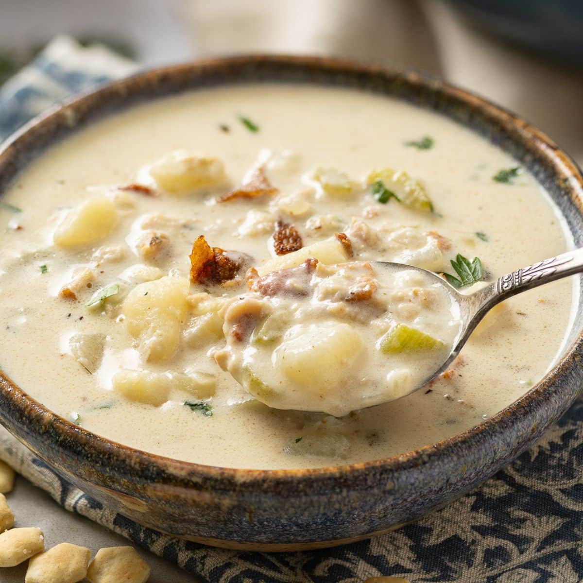 Spoonful of clam chowder coming out of the bowl.