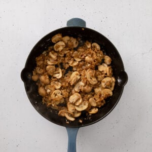 Sauteed mushrooms and onions fried in a skillet.