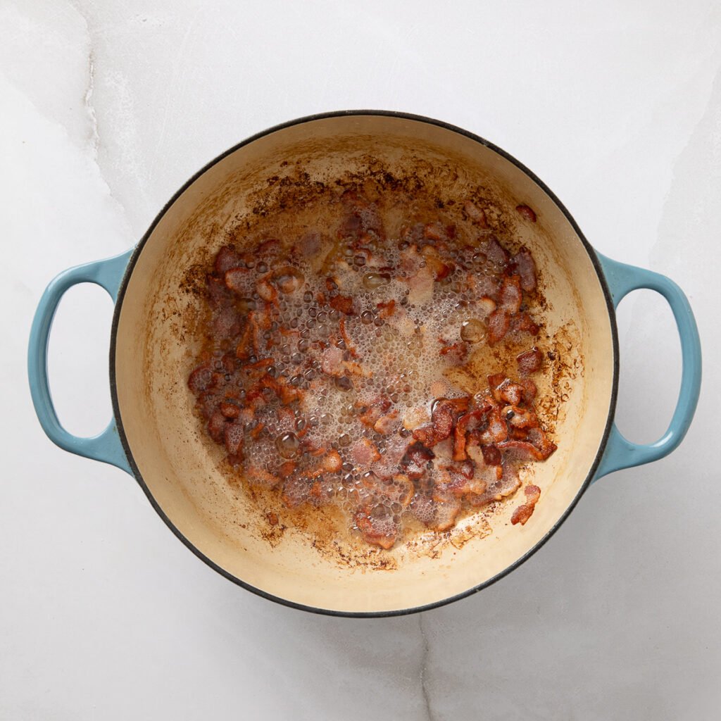 Crispy chopped bacon pieces in a Dutch oven.