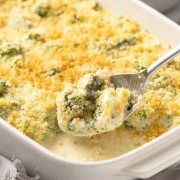 Scoop of broccoli cheese casserole coming out of a baking dish.