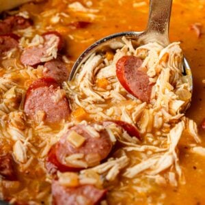 Close of up of shredded chicken, sausage slices and rice in a hearty gumbo broth.