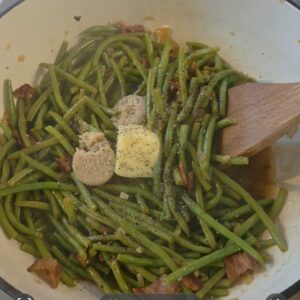 Frozen green beans added to the bacon and onion mixture, with brown sugar and butter pats.