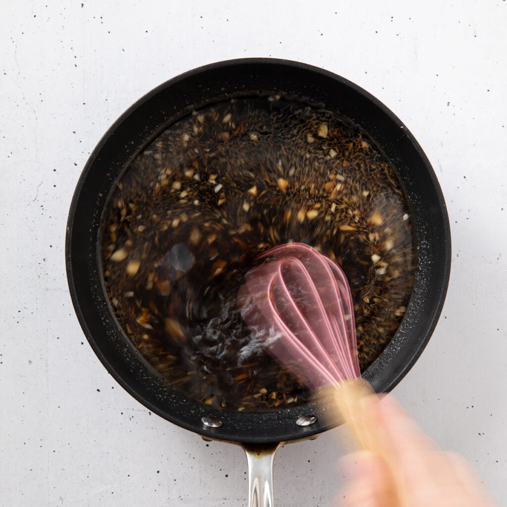 Teriyaki sauce being whisked in a skillet.