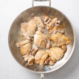 Golden brown chicken thighs resting in a skillet.