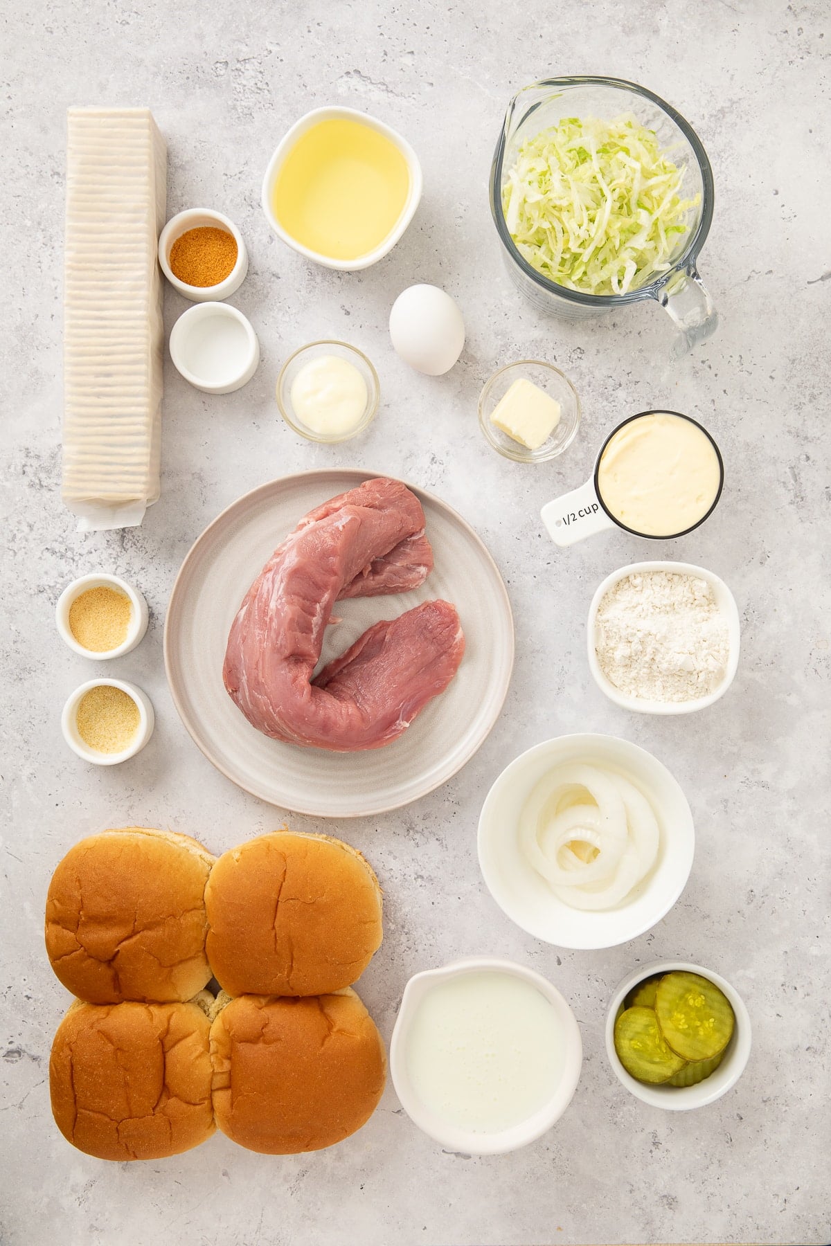 Ingredients laid out are used to prepare fried pork tenderloin to make sandwiches.