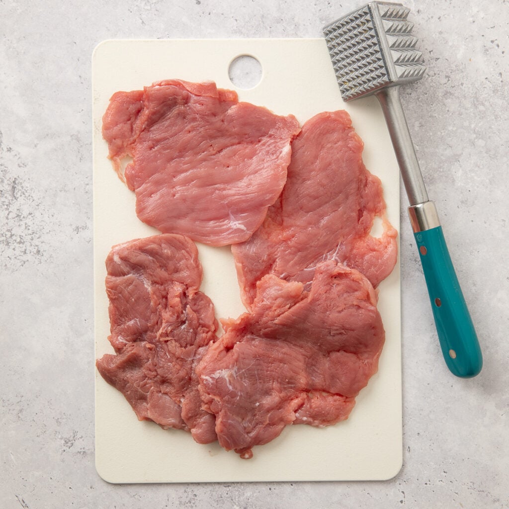 4 pieces of flattened raw pork tenderloin.