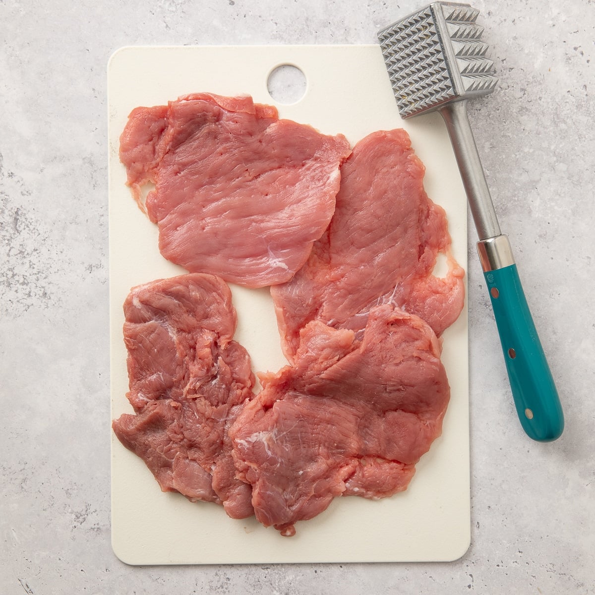 4 pieces of flattened raw pork tenderloin.