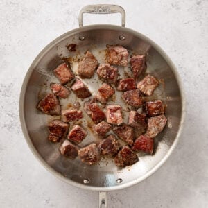 sirloin pieces being browned in a skillet for sweet and sour beef