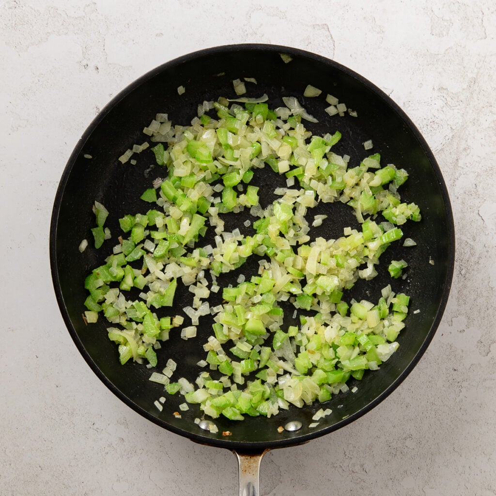 Diced onions and celery sauteeing in a saute pan.