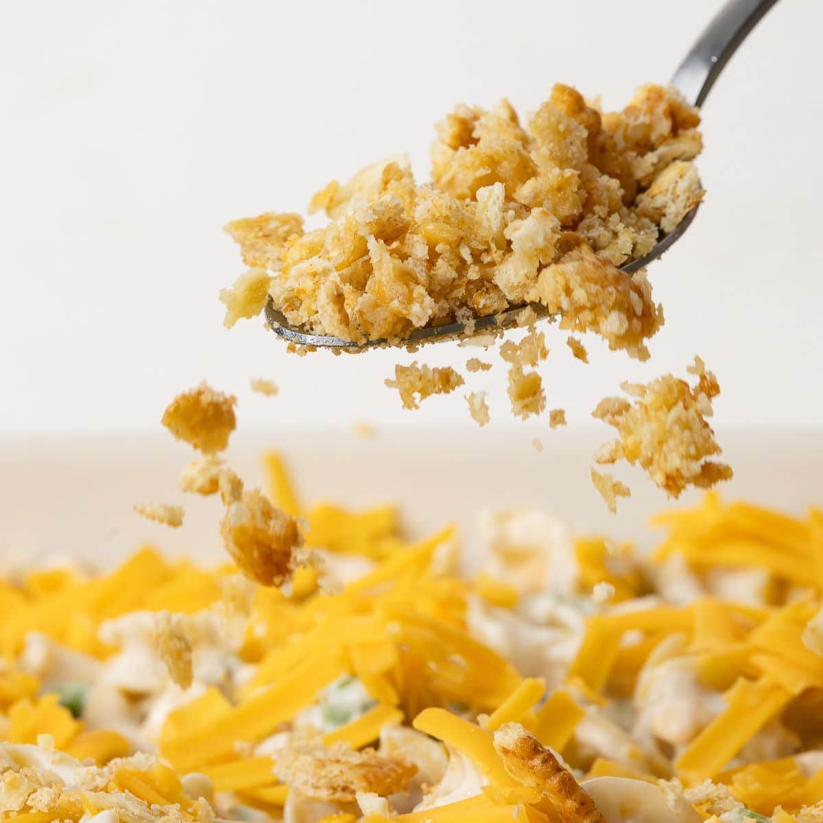 Buttery ritz crackers mixture being sprinkled over a tuna noodle casserole.