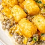 Ground beef and veggies in a gravy with melted cheese and tater tots on top.