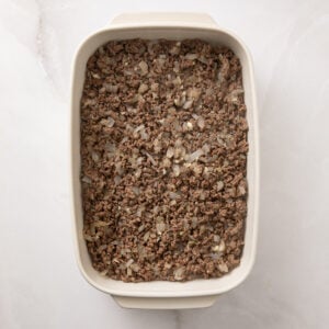 Browned hamburger and onions covering the bottom of a baking dish.