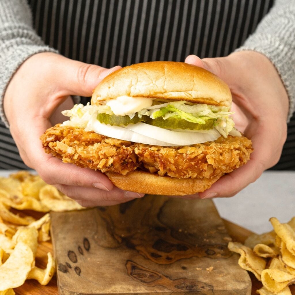 two hands holding pork tenderloin sandwich